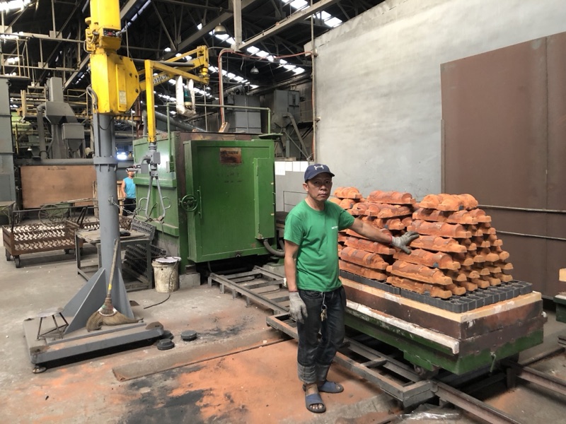A Metercor worker beside a stack of heavy castings in primer, ready for delivery