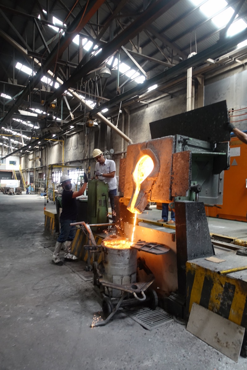 Pouring iron at the furnace into a sand mold, Metercor melt shop