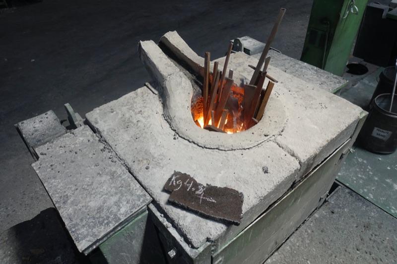 A crucible of molten metal glowing in the furnace, ready to pour