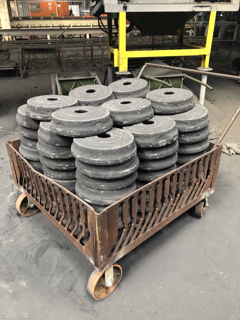 A cart stacked with round gray iron castings in the Metercor finishing area