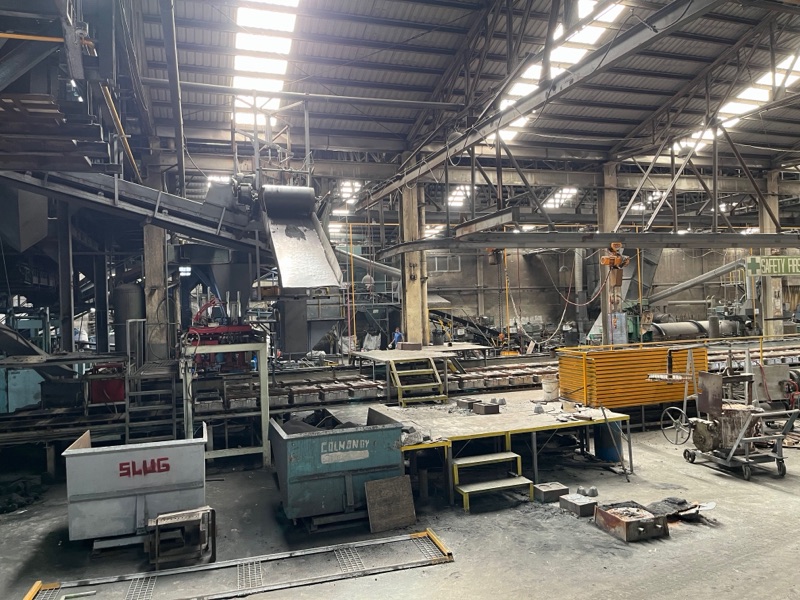 A long bay of the Metercor foundry with molding lines, cranes and castings on the floor
